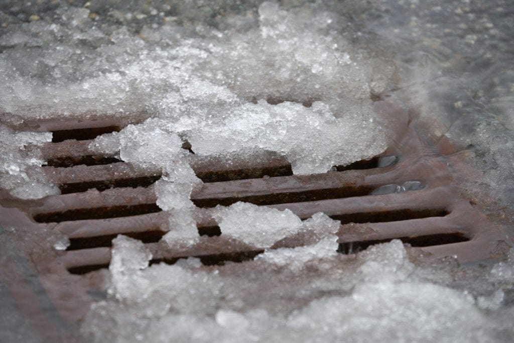 Heavy rain melts snow and pours into a storm drain after a snowfall
