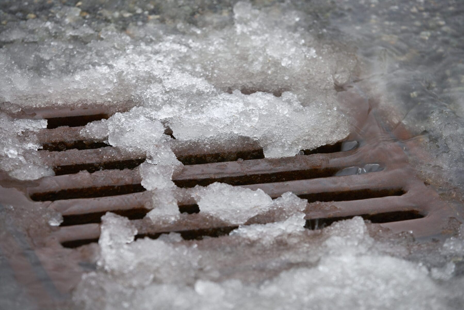 Heavy rain melts snow and pours into a storm drain after a snowfall