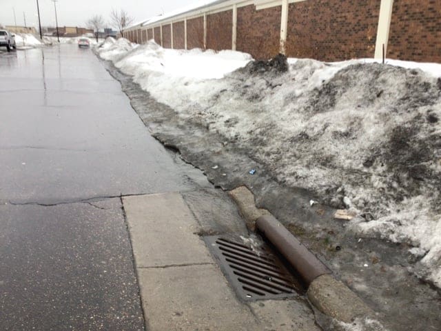 Snow piled above a catch basin in a parking lot