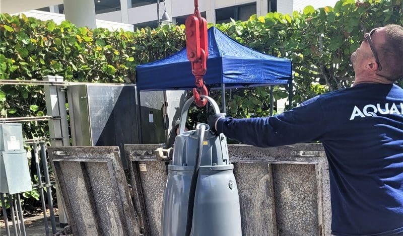 Man guides new lift station pump into place