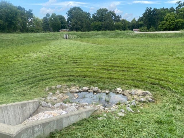 Outlet Control Structure with small puddle of water leading to a detention basin