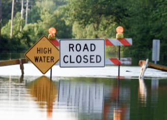 flooded road with "road closed" and "high water" signs