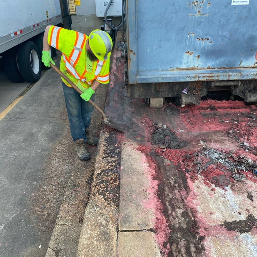 persons scraping mud off a concrete curb