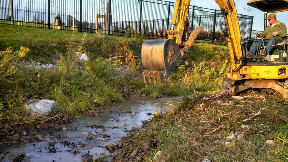 excavator digging into a stream