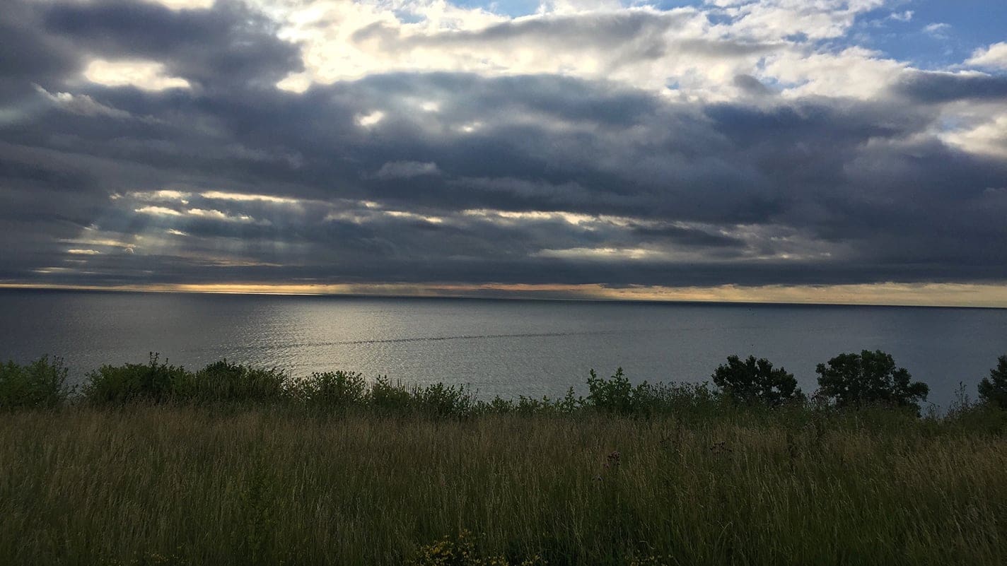 dark clouds with the sun peeking through over a lake