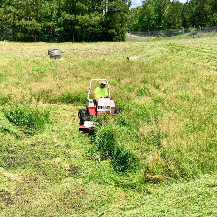 AQUALIS employee mowing a detention pond