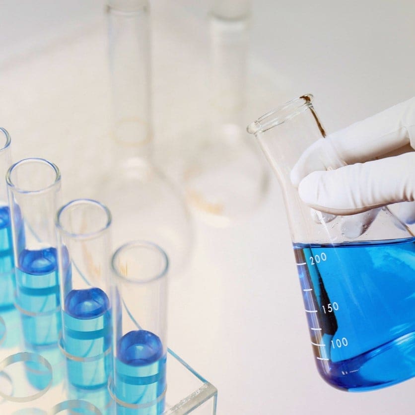 hand with glove holding a beaker