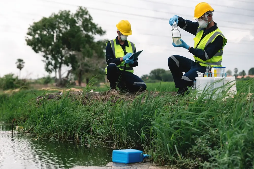 two people squatting by a pond testing the water