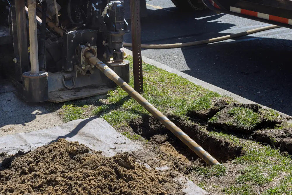 Trenchless Sewer Line Repair vs. Traditional Excavation: Which Method is Right for You? - AQUALIS Low angle view of trenchless sewer repair, fiber optic and water pipes with horizontal directional drilling technology machine work process