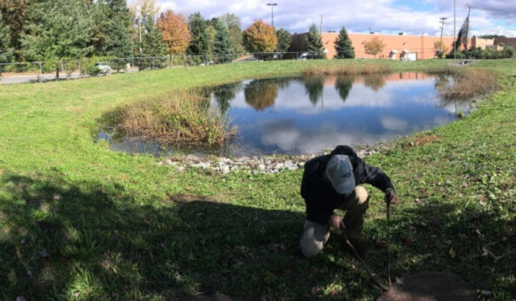 person digging a hole by a pond